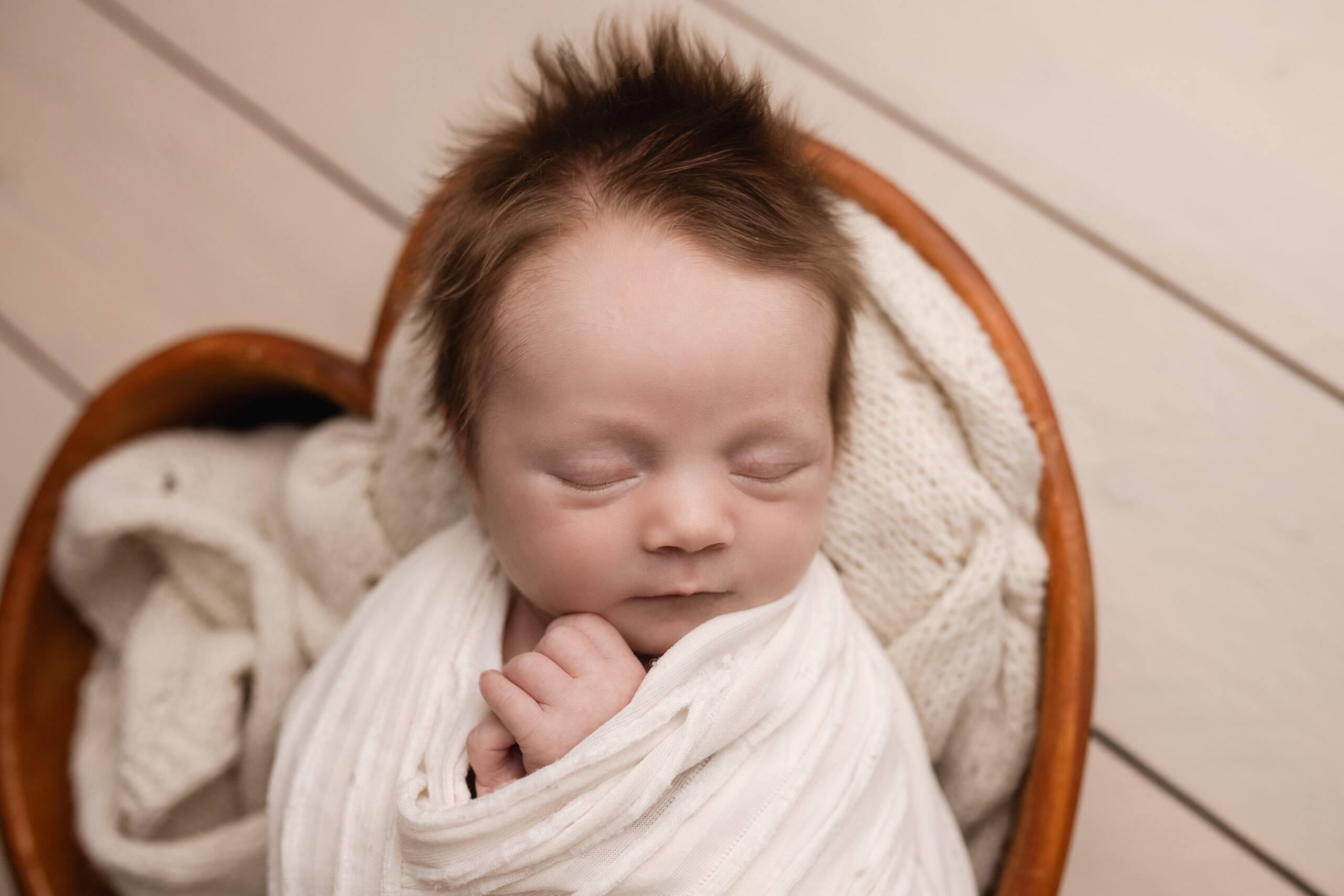 Pasgeboren baby met veel mooi haar in een houten mandje